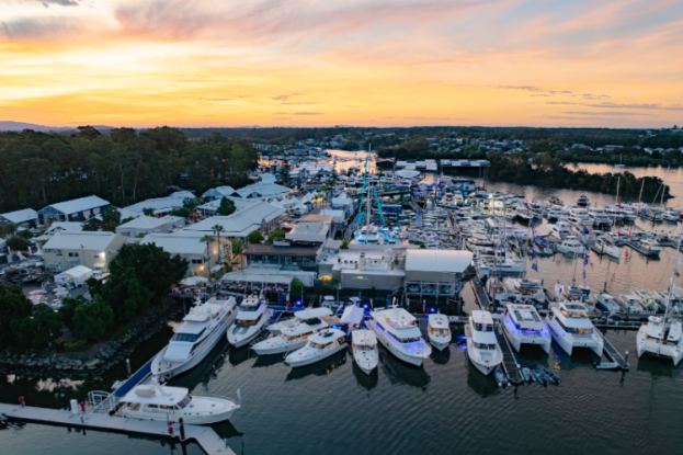 Sunset over a bustling marina with numerous boats docked along the piers and calm water fading into the horizon.